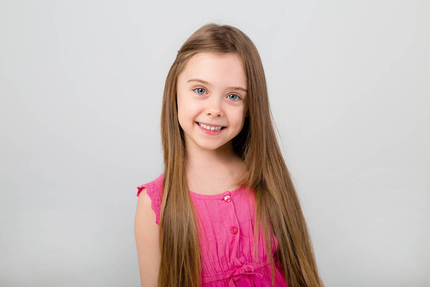 Porträt eines kleinen Mädchens in rosa Kleid auf weißem Hintergrund. Kids Emotions Konzept mit Kopierraum für Ihren Text - Foto, Bild