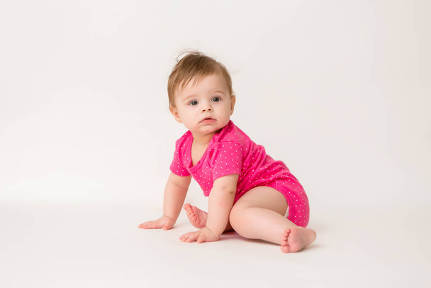 Photo of healthy baby girl in a pink bodysuit  on a white background. copy space picture with placement for your text or advertisement - Zdjęcie, obraz