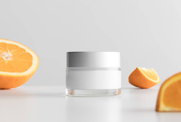 Krémes kozmetikai palack mockup narancsokkal egy fehér asztalon. - Fotó, kép