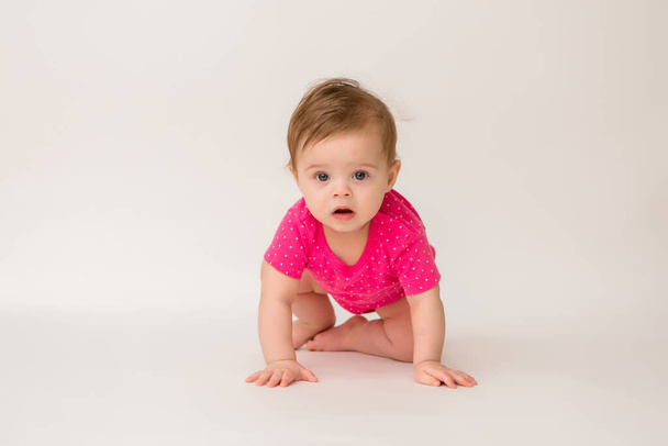 Photo of healthy baby girl in a pink bodysuit  on a white background. copy space picture with placement for your text or advertisement - Valokuva, kuva