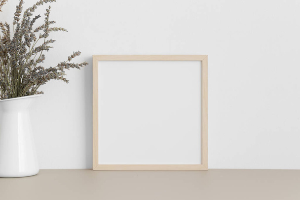 Square wooden frame mockup with a lavender in a vase on a beige table. - Foto, imagen
