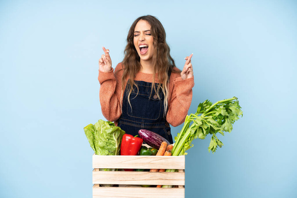 Фермер со свежими овощами в коробке со скрещенными пальцами - Фото, изображение
