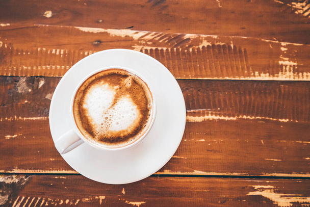 τέχνη latte σχήμα καρδιάς σε λευκό φλιτζάνι καφέ σε ξύλινο τραπέζι στο εστιατόριο καφέ - Φωτογραφία, εικόνα