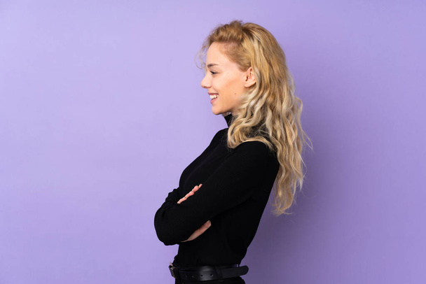 Mladá blondýna žena izolované na fialovém pozadí v boční pozici - Fotografie, Obrázek