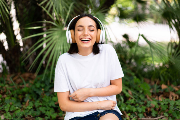 Young caucasian woman with headphones at outdoors smiling a lot - Photo, image