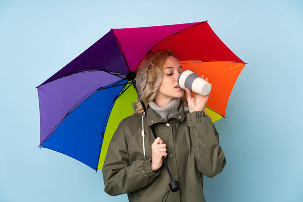 Egy kék háttérrel izolált esernyőt tartó nő - Fotó, kép