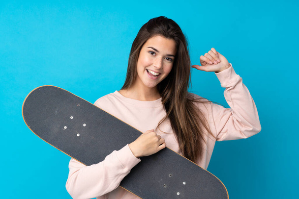 Teenager girl over isolated blue background with a skate with happy expression - Foto, immagini