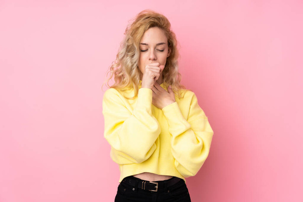 Young blonde woman wearing a sweatshirt isolated on pink background is suffering with cough and feeling bad - Photo, Image