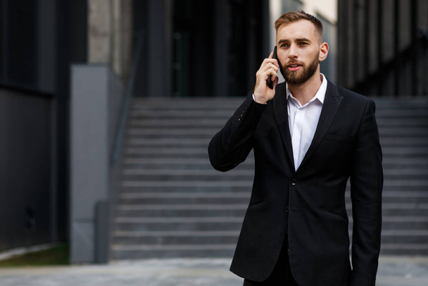 młody człowiek w formalnym garniturze rozmawia przez telefon - Zdjęcie, obraz