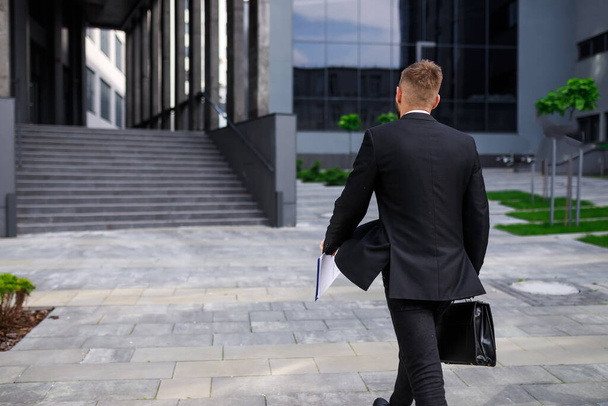 young man in formal suit with briefcase walking by office building - Photo, Image