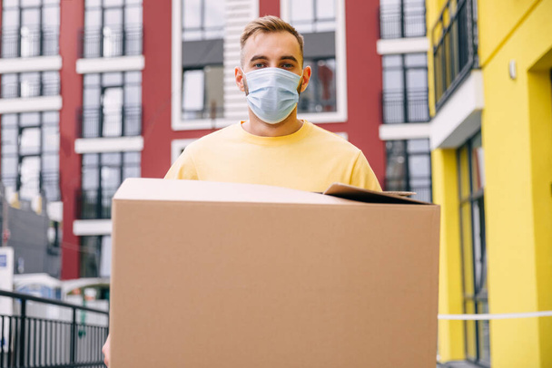 delivery worker wearing protective mask holding box - Фото, зображення