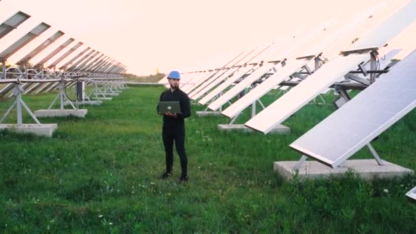 Inženýr pracující pomocí notebooku stojí vedle solárních baterií. - Záběry, video