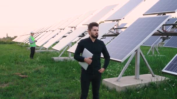 Προσωπογραφία του καυκάσιου βιομηχανικού εργάτη που στέκεται σε ένα οικολογικό πεδίο ηλιακών συλλεκτών. - Πλάνα, βίντεο
