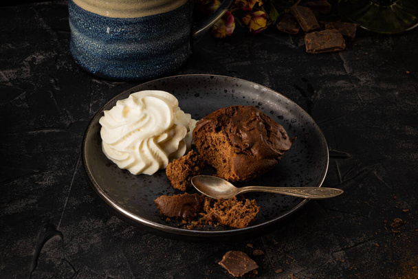 Homemade chocolate brownie with whipped cream on a plate. Dark photo. High quality photo - Φωτογραφία, εικόνα