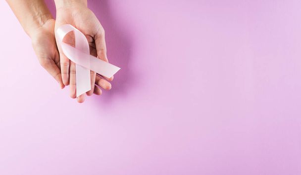 Mains tenant des rubans roses, sensibilisation au cancer du sein, noeud symbolique sensibilisant la couleur sur la tumeur du sein des femmes. Concept de santé, médecine et sensibilisation au cancer du sein. - Photo, image