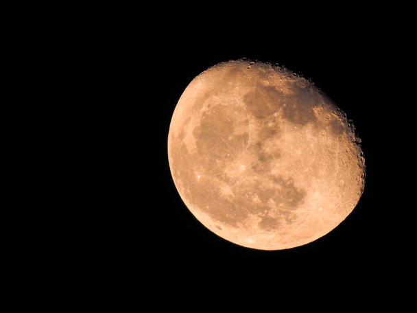 Подробный крупный план больших и розовых убывающих фаз луны на черном фоне, показывающий кратеры - Фото, изображение