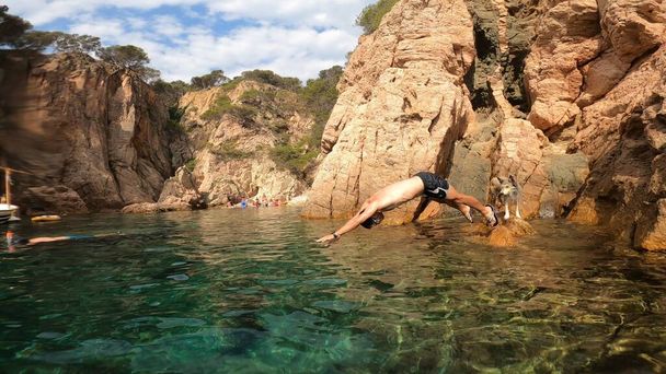 jonge man springen in de zee van een klif in costa brava - Foto, afbeelding