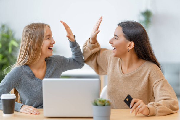 Two happy young women doing online purchases. Girls doing shopping at home. - Photo, image