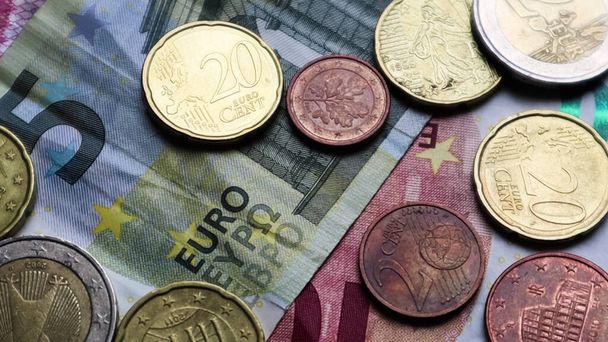 Eurobankovky a euromince jako pozadí. Střelen při pohledu na euro. Mince jsou na sebe naskládány na různých pozicích. Koncept peněz - Fotografie, Obrázek