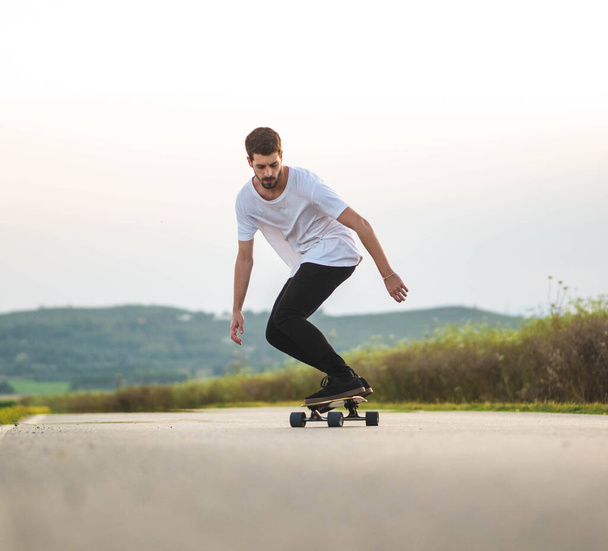 Um tiro foco raso de belo homem caucasiano montando um skate ao ar livre - Foto, Imagem