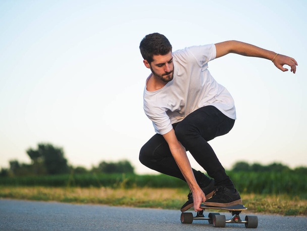 A shallow focus shot of handsome Caucasian male riding a skateboard at outdoors - Photo, Image