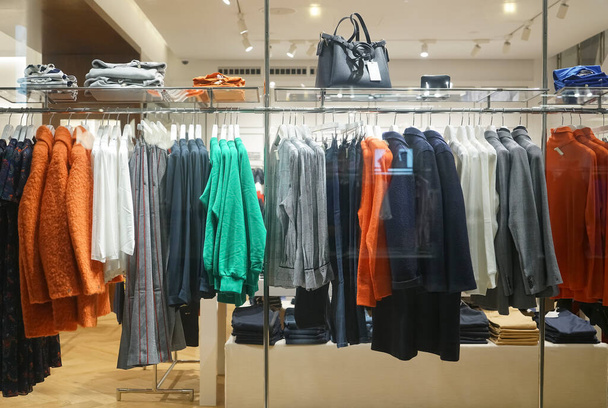 Stylish clothes and accessories in show room. row of many down jacket hanging on shelves in modern clothes store. - Foto, imagen