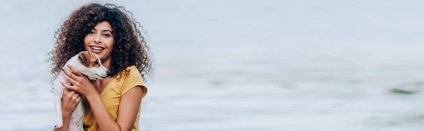 川の近くの喜びの女性の巨大なジャック・ラッセル・テリア・ドッグの水平画像 - 写真・画像