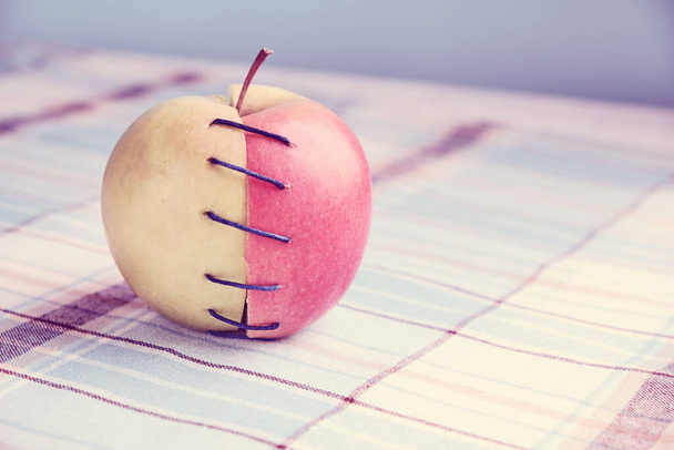 Δύο διαφορετικά μισά μήλου συνδεδεμένα με νήμα - Φωτογραφία, εικόνα