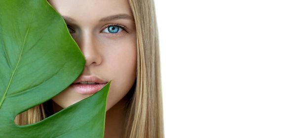 Blonde model with natural make up and green leaf isolated on white. Spa and wellness. Youth, teens and skin care concept.  Close up, selective focus, copyspace. - Foto, afbeelding