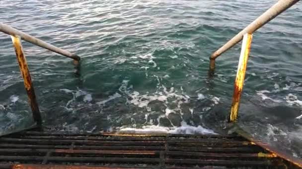 vecchie scale in ferro arrugginito con corrimano che scende in acqua blu - Filmati, video