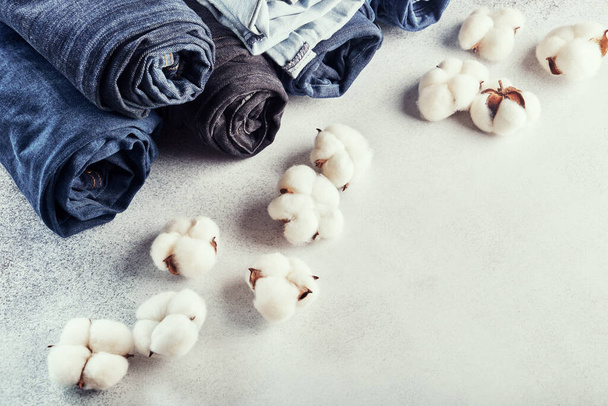 Jeansy zwinięte i kwiaty bawełny na jasnym tle - Zdjęcie, obraz