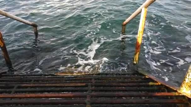 vieil escalier en fer rouillé avec rampe descendant en eau bleue - Séquence, vidéo