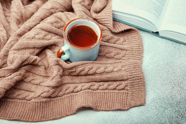 Tasse heißer Tee, aufgeschlagenes Buch und warme Strickdecke - Foto, Bild