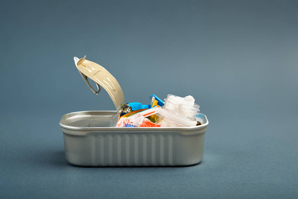 Open tin can. Plastic waste instead of fish inside. Ocean plastic pollution concept - Foto, afbeelding