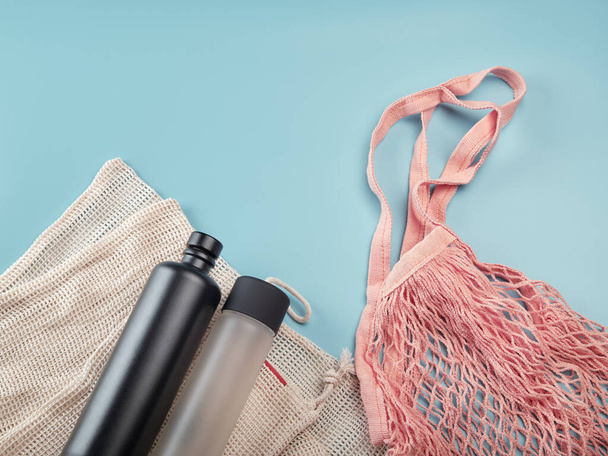 Cotton eco bags and water bottles on blue background. Zero waste concept - Photo, image