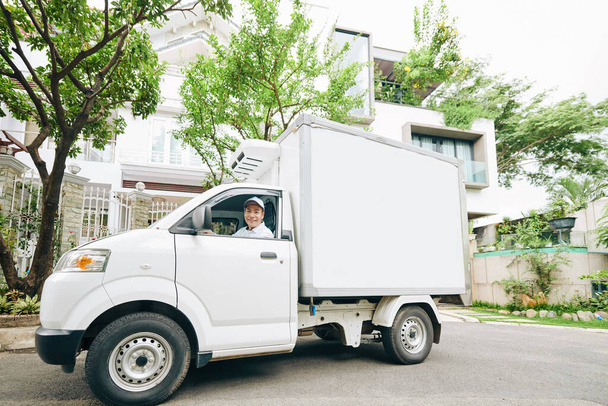 Χαμογελαστός νεαρός Βιετναμέζος οδηγός φορτηγού γάλακτος και παράδοση γαλακτοκομικών προϊόντων - Φωτογραφία, εικόνα