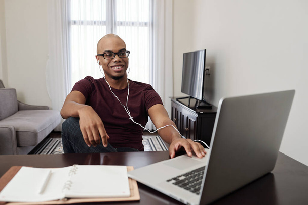 Lachende knappe jonge zwarte man wonen online klasse of kijken webinar op laptop - Foto, afbeelding