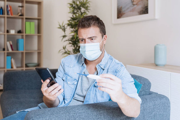 インフルエンザの症状を持つ男が温度をチェックし、医者を呼び出す - 写真・画像
