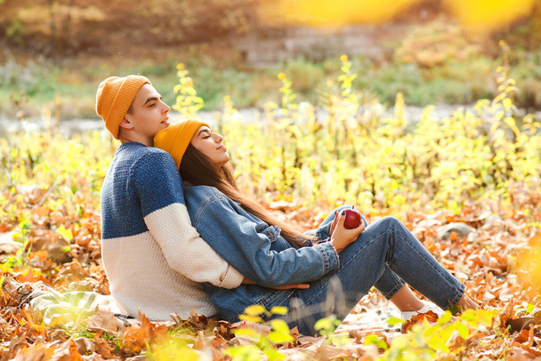 秋を楽しむおしゃれなカップル。ファッション、ライフスタイル、秋の休暇。秋の葉の間に横たわるスタイリッシュな男と女。若いカップルは秋に一緒に楽しんでいます。愛. - 写真・画像