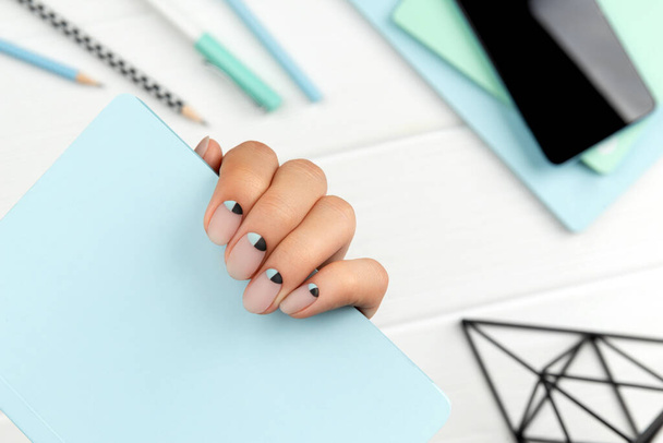 Groomed womans hand with creative nail design holding note pad - Fotoğraf, Görsel