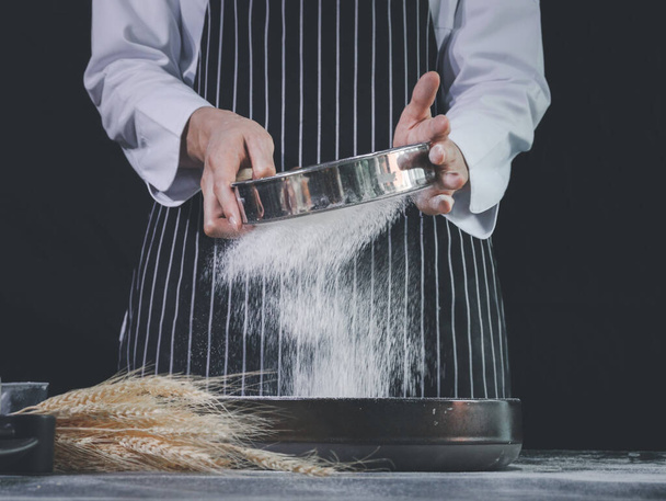 Bakery man sifting flour into a bowl, preparing bread dough, kneading the dough. Hands with flour splash, food homemade bakery concept - Photo, image