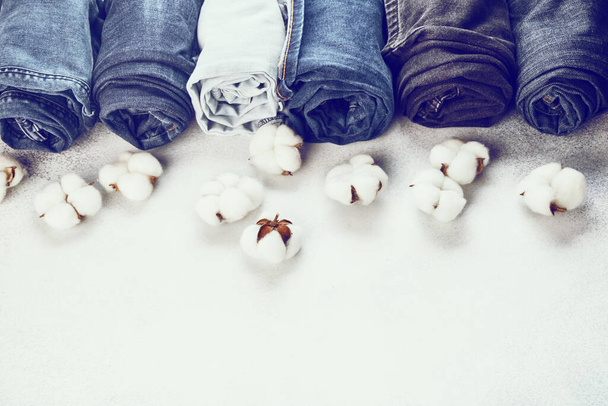 Rangée de jeans roulés et de fleurs de coton sur fond clair - Photo, image