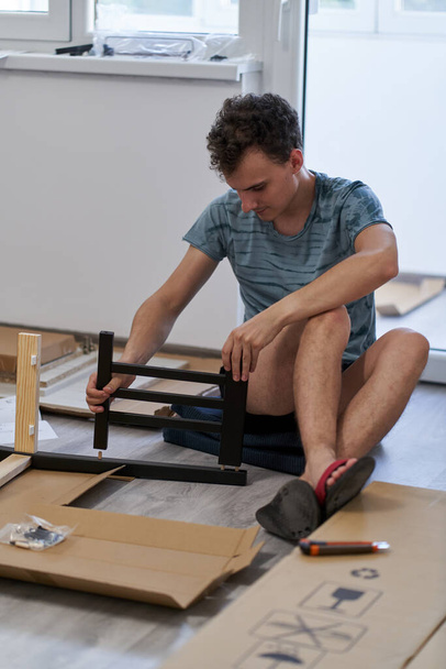 Young man assembling furniture in his new home, new life concept - Foto, Imagen