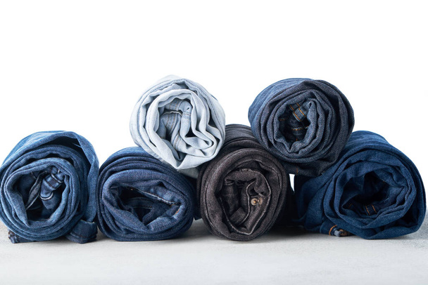 Stack of different rolled jeans on white background - Fotoğraf, Görsel