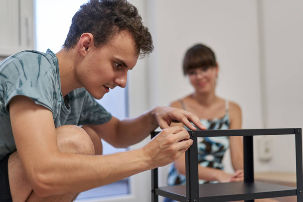 Young couple assembling furniture in their new home, new life concept - 写真・画像