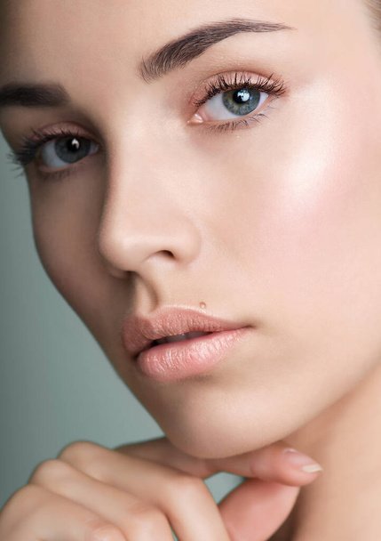 Close up of beautiful young woman with clean perfect skin. Portrait of beauty model with natural nude make up and and hand with manicure touching face. Spa, skincare and wellness. Closeup, background, copyspace. - Φωτογραφία, εικόνα