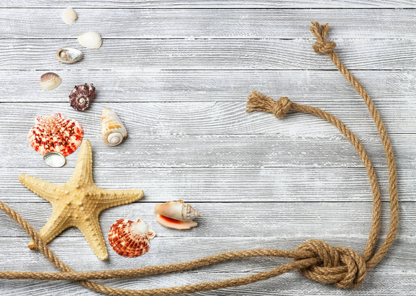 Seashells, hvězdice a lano na lehkém dřevěném pozadí - Fotografie, Obrázek