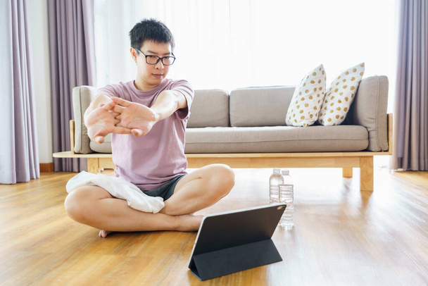 Új normál edzés otthon Egy 35-40 éves ázsiai férfi, barna bőrrel, házi gyakorlattal. gyakorlás a nappaliban. - Fotó, kép