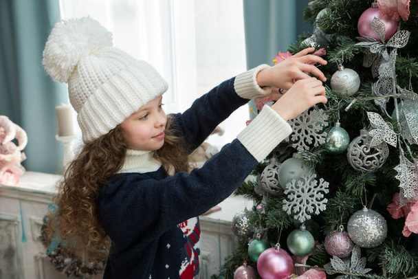 Little girl  decorates the Christmas tree. X-mass and New year waiting and celebration concept. Holiday home decoration. - Φωτογραφία, εικόνα