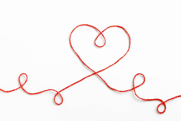 Red woolen thread in the shape of heart on white background. Valentine's Day - Photo, Image